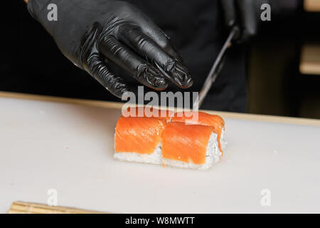 Maschio di taglio a mano con coltello Salmone rotoli Foto Stock