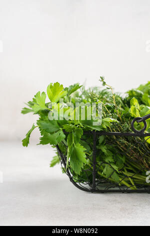 Cestello con una varietà di fresco verde erbe culinarie su sfondo grigio. Ingredienti organici per la cottura.