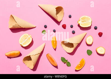 Frutta fresca e croccante coni di cialda su sfondo rosa nella luce solare Foto Stock
