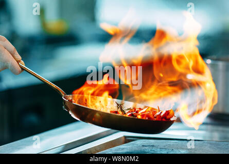 Cucina moderna. I cuochi preparano pasti sul fornello nella cucina del ristorante o albergo. Il fuoco in cucina. Foto Stock