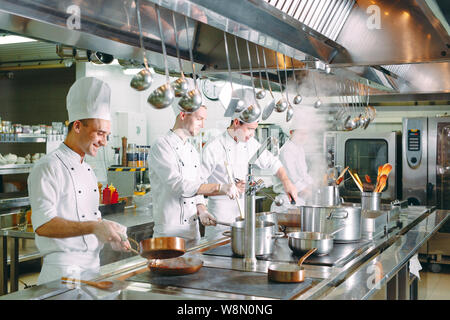Cucina moderna. I cuochi preparano pasti sul fornello nella cucina del ristorante o albergo. Il fuoco in cucina. Foto Stock