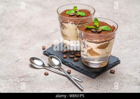 Tiramisù classico dessert in un bicchiere sulla pietra che serve di bordo su sfondo di calcestruzzo Foto Stock