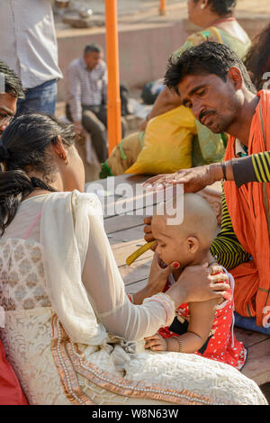 Un giovane bambino ha la sua testa rasata come parte degli Indù Mundan rituale per ripulire il suo passato di vita, Varanasi, Uttar Pradesh, India, Asia del Sud Foto Stock