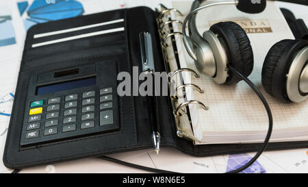 Close-up, cuffia giacente su un blocco note di agenda elettronica. Call center tabella. Foto Stock