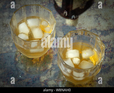 Due bicchieri di whiskey con ghiaccio su un contatore ed elegante Foto Stock
