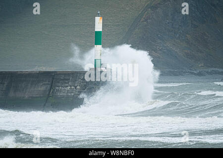 10 ago 2019 Aberystwyth Wales UK. Regno Unito: Meteo gale force vento con raffiche fino a oltre 50km/h e il mare in tempesta pastella il faro del porto, e rende la vita difficile per i pedoni in Aberystwyth come unseasonably bagnato e ventoso spazia su gran parte dell'ovest del Regno Unito , portando gravi perturbazioni per viaggiare e forzare la cancellazione di molti eventi all'esterno. Credito foto Keith Morris/Alamy Live News Foto Stock