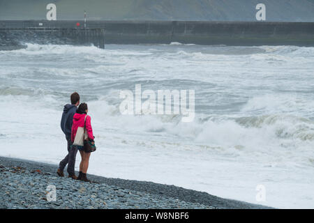 10 ago 2019 Aberystwyth Wales UK. Regno Unito: Meteo gale force vento con raffiche fino a oltre 50km/h e il mare in tempesta pastella il faro del porto, e rende la vita difficile per i pedoni in Aberystwyth come unseasonably bagnato e ventoso spazia su gran parte dell'ovest del Regno Unito , portando gravi perturbazioni per viaggiare e forzare la cancellazione di molti eventi all'esterno. Credito foto Keith Morris/Alamy Live News Foto Stock