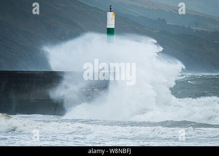 10 ago 2019 Aberystwyth Wales UK. Regno Unito: Meteo gale force vento con raffiche fino a oltre 50km/h e il mare in tempesta pastella il faro del porto, e rende la vita difficile per i pedoni in Aberystwyth come unseasonably bagnato e ventoso spazia su gran parte dell'ovest del Regno Unito , portando gravi perturbazioni per viaggiare e forzare la cancellazione di molti eventi all'esterno. Credito foto Keith Morris/Alamy Live News Foto Stock