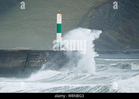 10 ago 2019 Aberystwyth Wales UK. Regno Unito: Meteo gale force vento con raffiche fino a oltre 50km/h e il mare in tempesta pastella il faro del porto, e rende la vita difficile per i pedoni in Aberystwyth come unseasonably bagnato e ventoso spazia su gran parte dell'ovest del Regno Unito , portando gravi perturbazioni per viaggiare e forzare la cancellazione di molti eventi all'esterno. Credito foto Keith Morris/Alamy Live News Foto Stock