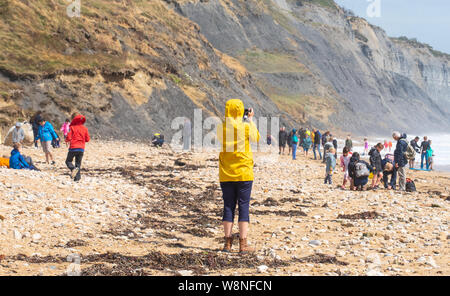 Charmouth, Dorset, Regno Unito. Il 10 agosto 2019. Meteo REGNO UNITO: vacanzieri avventurarvi in un blustery giornata al villaggio sul mare di Charmouth come unseasonably strong a sud-ovest si snoda continuano ad impasto lungo la costa sud occidentale il sabato pomeriggio. Le condizioni tempestose non scoraggiare i cacciatori di fossili sulla spiaggia Charmouth. Credito: Celia McMahon/Alamy Live News. Foto Stock