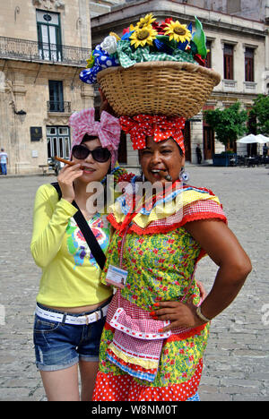 Colorata scena di strada di pretty tourist fumatori di sigaro cubano con locale street performer Foto Stock