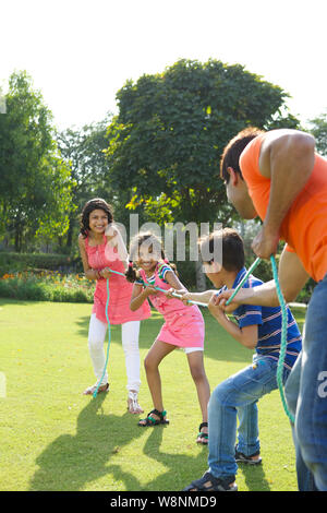 Family playing tug of war in a garden Stock Photo