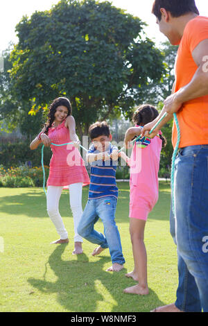 Family playing tug of war in a garden Stock Photo