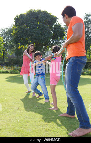 Family playing tug of war in a garden Stock Photo