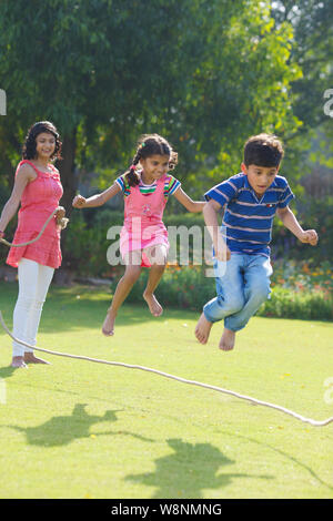 Famiglia che gioca con una corda in un giardino Foto Stock