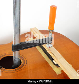 La riparazione di una chitarra e il servizio di assistenza - fix colla chitarra acustica Bridge Foto Stock