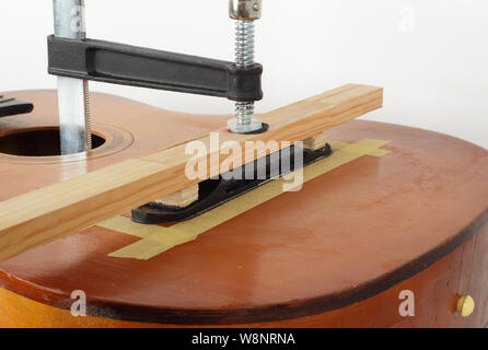 La riparazione di una chitarra e il servizio di assistenza - fix colla chitarra acustica Bridge Foto Stock