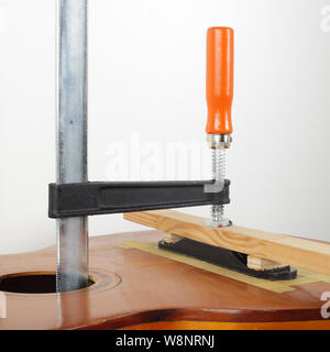 La riparazione di una chitarra e il servizio di assistenza - fix colla retrò chitarra acustica Bridge Foto Stock