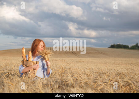 Redhead donna con prodotti da forno a ripe campo di grano Foto Stock