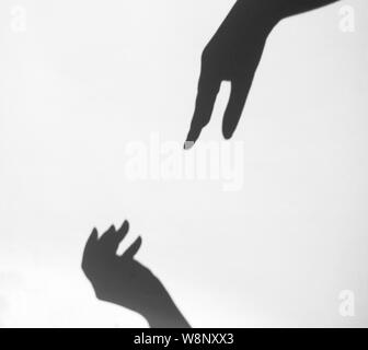 Due le mani delle donne per raggiungere ogni altro. Mano silhouette femminile e maschile insieme. Foto Stock