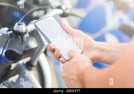 L'uomo utilizza lo smartphone per le transazioni bancarie online noleggio bicicletta Foto Stock