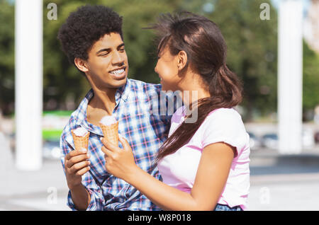 Sorridente giovane adolescente avente gustosi gelati su una data all'aperto Foto Stock