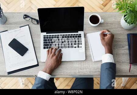 Imprenditore nero lavorando sul suo laptop seduto sul posto di lavoro Foto Stock