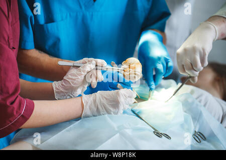 Gruppo di chirurghi al lavoro che operano in sala operatoria. Medicina di rianimazione team indossando maschere di protezione Foto Stock
