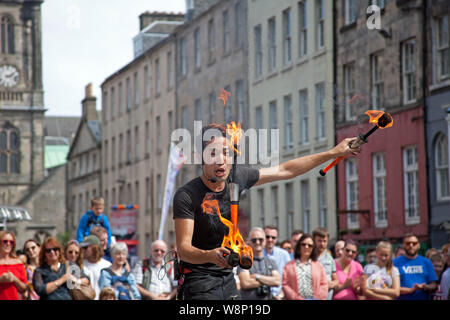 Il Royal Mile di Edimburgo, Scozia, Regno Unito. 10 Ago, 2019. Edinburgh Fringe street performer SYO! Dal Giappone ha lavorato ad un ritmo travolgente per divertire il pubblico con un emozionante spettacolo di fuoco il secondo sabato sul medio-alta cerchio passo sulla strada alta. Credito: Arch bianco/Alamy Live News Foto Stock