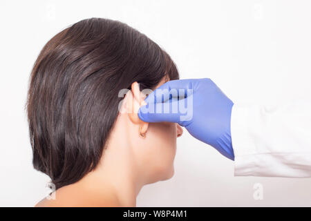 Un chirurgo plastico medico esamina un paziente s ragazza s orecchie prima di eseguire un intervento chirurgico orecchie Foto Stock