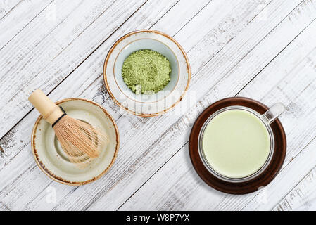 Tè verde Matcha latte con matcha in polvere e mescolare con una frusta di bambù. Vista dall'alto. Foto Stock