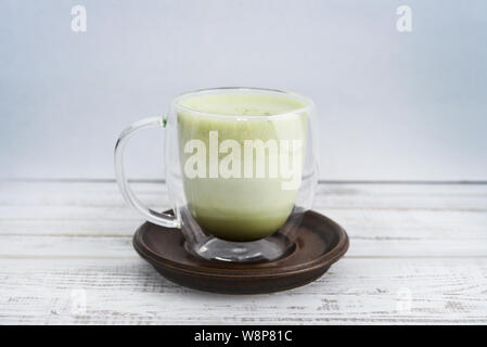 Tè verde Matcha latte nella tazza di vetro su sfondo di legno closeup Foto Stock