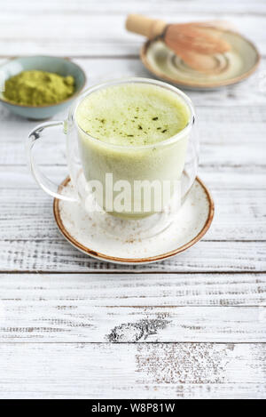 Tè verde Matcha latte con matcha in polvere e mescolare con una frusta di bambù su sfondo di legno closeup Foto Stock