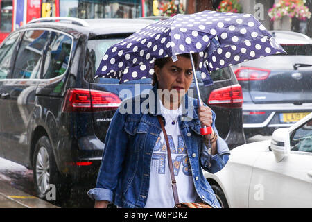 Londra, Regno Unito. 10 Ago, 2019. Una donna è visto sotto un ombrello durante una breve doccia a pioggia a Londra. Credito: Steve Taylor/SOPA Immagini/ZUMA filo/Alamy Live News Foto Stock