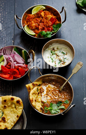 Il curry indiano pasto con lenticchie nero dal, piccante di patate, riso, pane naan e raita Foto Stock