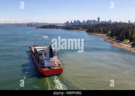 Vista aerea di un contenitore grande nave passando da Stanley Park con il centro città in background. Preso dal Ponte Lions Gate, Vancouver, British col Foto Stock