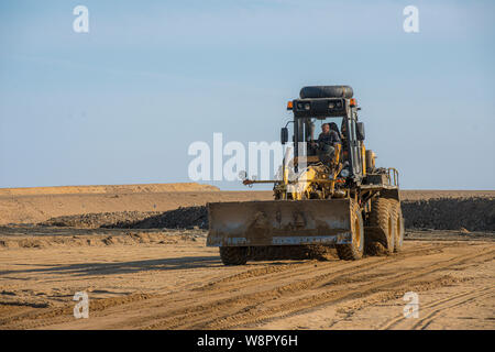 Livellamento della livellatrice ghiaia sulla strada sito in costruzione. Foto Stock