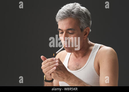 Uomo senior di accendere una sigaretta Foto Stock