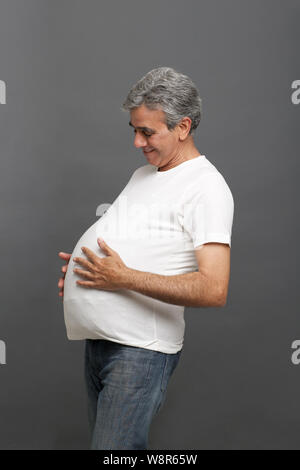 Uomo anziano fingendo di essere una donna incinta Foto Stock