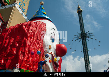 16.06.2019, Vienna, Austria, Europa - un gigante clown faccia e una chairoplane presso il parco divertimenti del Wiener Prater. Foto Stock