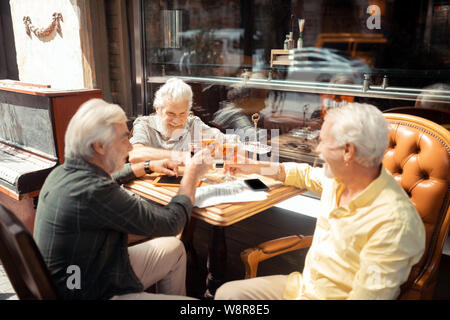 Tre uomini pensionati celebrando la riunione e il consumo di alcool Foto Stock