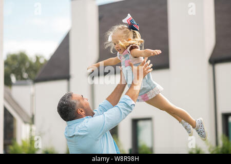 Figlia volare in aria mentre si divertono con il suo papà Foto Stock