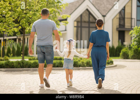 Paio di imprenditori a piedi con la loro bambina in città Foto Stock