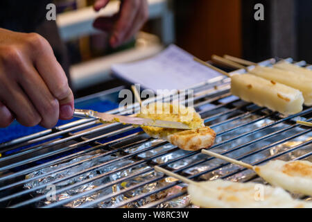 Aggiunta di topping a Giapponese riso glutinoso su stick dessert Foto Stock