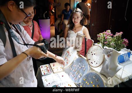 (190811) -- DALI, 11 Agosto, 2019 (Xinhua) -- i turisti selezionare accessori presso un negozio nella città vecchia di Dali, a sud-ovest della Cina di Provincia di Yunnan, il 10 agosto 2019. I turisti sono venuti qui per godere di incantevole vista notturna il cibo locale e attraente prestazioni durante le ore notturne. (Xinhua/Qin Qing) Foto Stock