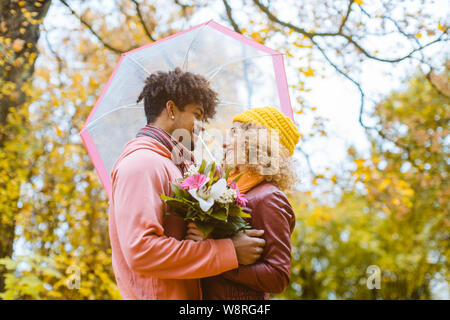 L uomo e la donna di diversa etnia abbracciando in autunno Foto Stock