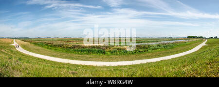 Panoramica vista composita di un concreto percorso in bicicletta lungo la nuova Reevediep canale del fiume e zone umide adiacenti vicino a Kampen, Paesi Bassi al di sotto di una s Foto Stock