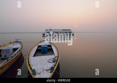 Imbarcazioni moderne al fiume Gange a Varanasi India. Moderno sistema di cottura a vapore di carburante barche condividi itinerari turistici tradizionali lungo con vecchie barche di legno Foto Stock