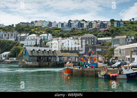 Barche da pesca lo scarico del pesce in banchina. Mevagissey, Cornwall, England, Regno Unito Foto Stock