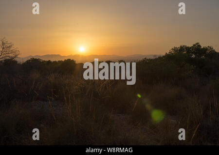 Un tramonto dietro le montagne durante una calda serata estiva in agosto visto oltre la città di Alicante Foto Stock